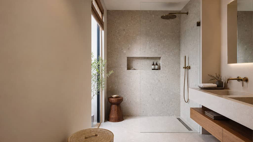 Baño de piso con ducha de obra, mampara de cristal y lavabo doble integrado