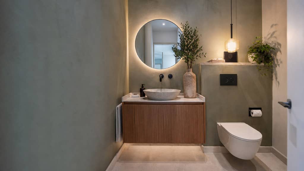 Baño secundario de piso con lavabo de microcemento e inodoro suspendido