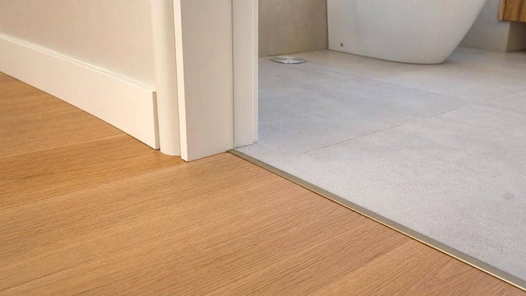 Perfil de transición entre parquet y baldosa en acceso a baño