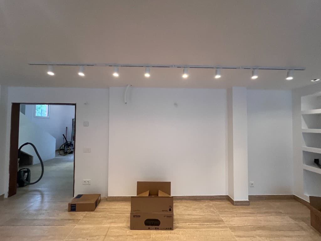 Salón reformado preparado para cine en casa con estanterías empotradas e iluminación en rail
